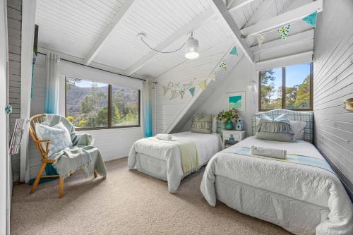 a bedroom with two beds and a chair and a window at Cedar Country Retreat in Halls Gap