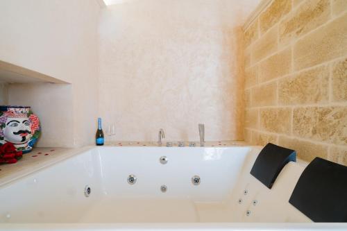 a white bath tub in a bathroom with a bottle of wine at Corte Donato Grasso Relax - Salento Selection in Alessano