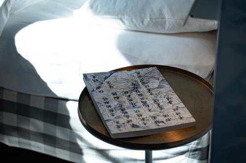 a table with a book on it next to a bed at Boutique & Art Hotel Helvetia in Zurich
