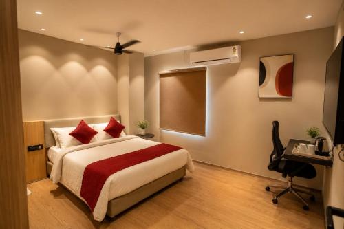 a bedroom with a bed with red pillows and a desk at Hotel Vdara Bliss in Vijayawāda