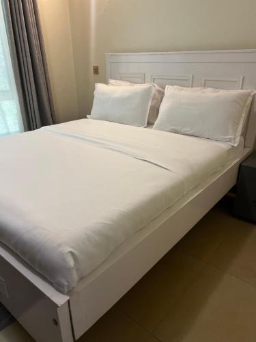 a large bed with white sheets and pillows at Hanik Homes in Kampala