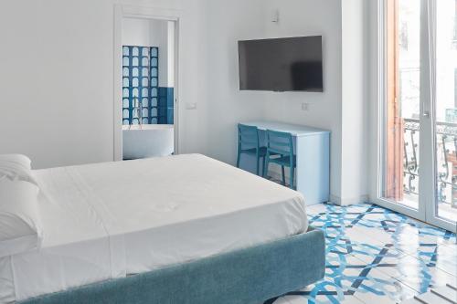a white bedroom with a bed and a blue chair at Maison Blu Royal in Amalfi
