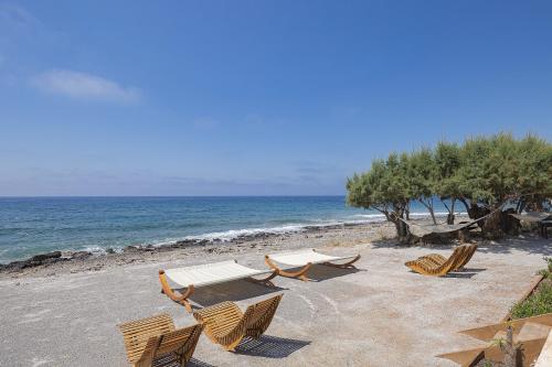 a group of chairs and a bench on a beach at Moonlight Villas Calypso - Sleek Coastal Living by etouri in Koutsourás