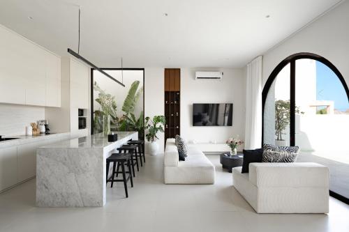 an open kitchen and living room with white furniture at Casa Infinity Villa 2 - Oasis 3BR & Ocean View by BaliSuperHost in Mengwi