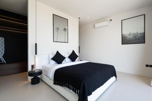 a bedroom with a black and white bed and two pictures at Casa Infinity Villa 2 - Oasis 3BR & Ocean View by BaliSuperHost in Mengwi