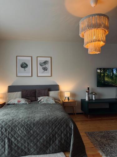 a bedroom with a bed and a chandelier at The Garden room in Ikšķile