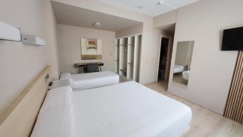 ein weißes Schlafzimmer mit einem großen Bett und einem Spiegel in der Unterkunft Hotel Alaiz in Beriáin
