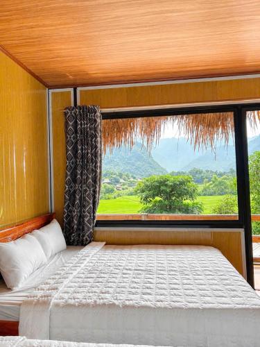 a bed in a room with a large window at Green Homestay Mai Chau in Mai Châu