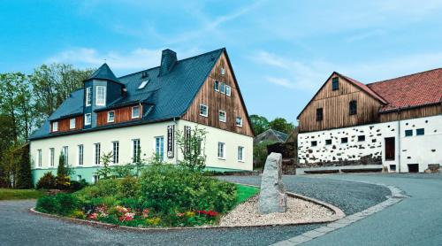 a large white building with a black roof at Landhotel Gutshof in Hartenstein