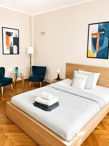 a white bedroom with a large bed with two chairs at Apartman Lena in Belgrade