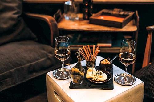 a table with two glasses of wine and snacks at Tante ALMA Bristol Hotel in Frankfurt