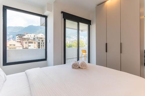 a bedroom with a large white bed with two towels at Les Jardins Kaslik in Al Bāţiyah