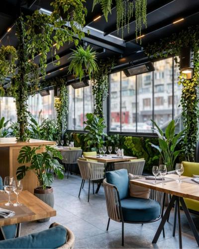 a restaurant with tables and chairs and plants at Holiday Inn Bucharest - Times by IHG in Bucharest
