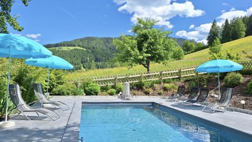 a swimming pool with chairs and umbrellas at Vordersattlegghofhütte in Hüttau