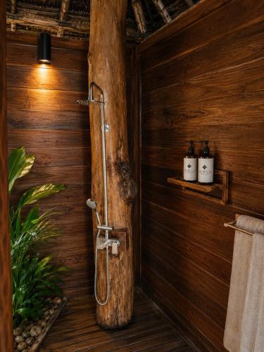 a bathroom with a wooden wall with a shower in it at Tiki Beach Economy in Paje