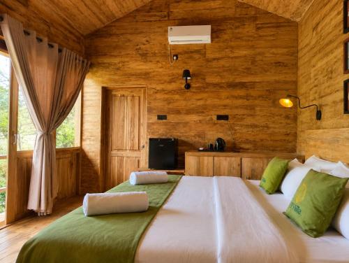 a bedroom with a large bed in a room with wooden walls at J Villa Sigiriya - Private Pool Chalets in Dambulla