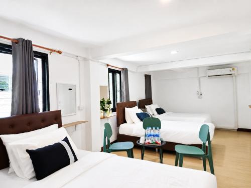 a hotel room with two beds and a table and chairs at The 789 House in Chiang Mai