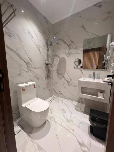 a white bathroom with a toilet and a sink at الديار الفاخرة للشقق المخدومة - جيزان in Jazan