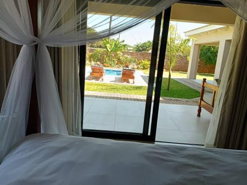 a bedroom with a bed and a view of a pool at Judith & Sylvester Hideaway in Victoria Falls