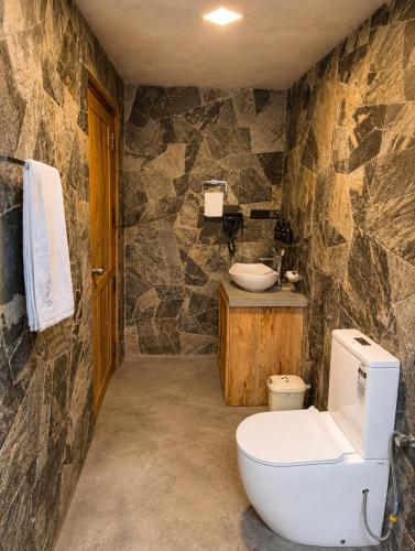 a stone bathroom with a toilet and a sink at J Villa Sigiriya - Private Pool Chalets in Dambulla