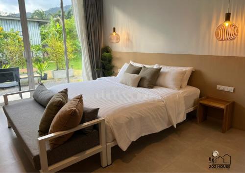 a bedroom with a large bed and a large window at 202 HOUSE near Bangtao Muay Thai & MMA in Ban Thalat Choeng Thale