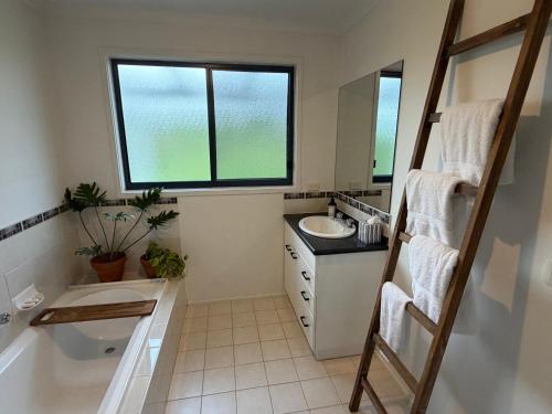 a bathroom with a tub and a sink and a window at Oak Vue cottage in Korumburra