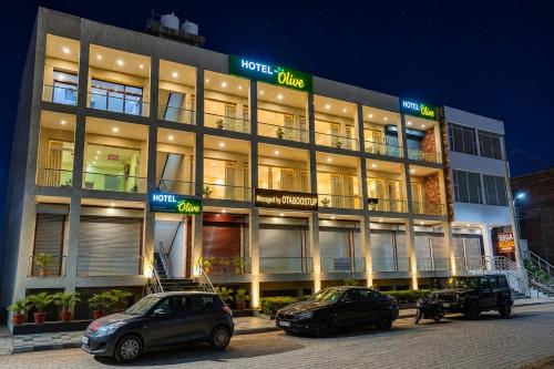 two cars parked in front of a building at night at Hotel Olive Sunny Enclave, Near Airport Road, Mohali in Kharar