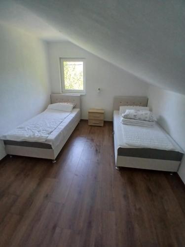 two beds in a room with a wooden floor at Apartman Nature in Konjic