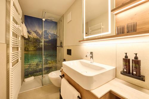a bathroom with a sink and a toilet and a window at Dorint Sporthotel Garmisch-Partenkirchen in Garmisch-Partenkirchen
