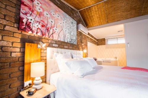 a bedroom with a white bed and a brick wall at Farnham Court Motel and Restaurant in Morwell