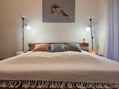 a bedroom with a large white bed with two lamps at Odavagyok Vendégház in DiÃ³sviszlÃ³