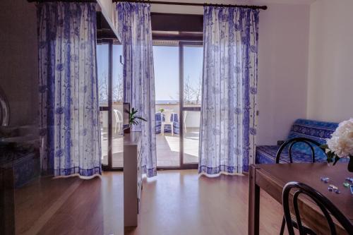 a living room with blue curtains and a dining room table at Le Terrazze in Follonica