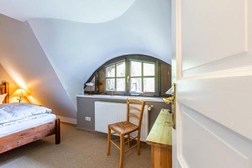 a bedroom with a bed and a chair and a window at Meermaler in Ahrenshoop