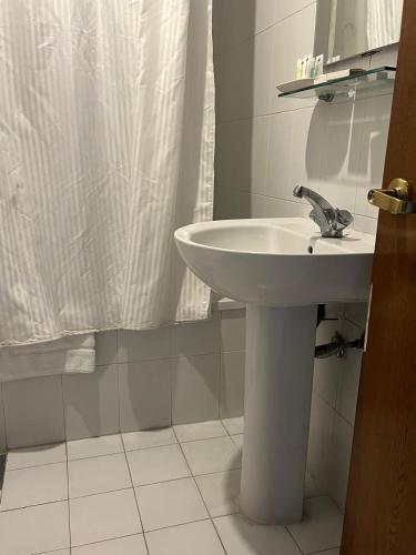 a bathroom with a sink and a shower curtain at Manuella Hotel in Ed Dkârîne