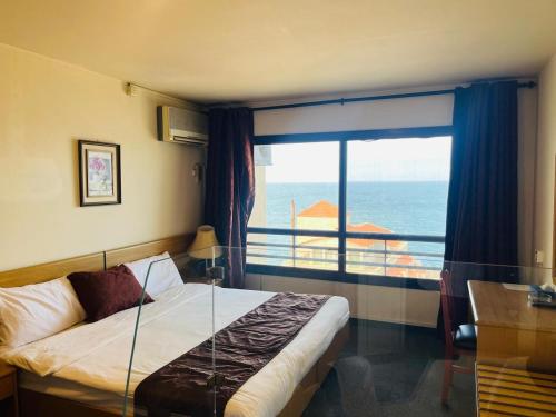 a bedroom with a bed with a view of the ocean at Manuella Hotel in Ed Dkârîne