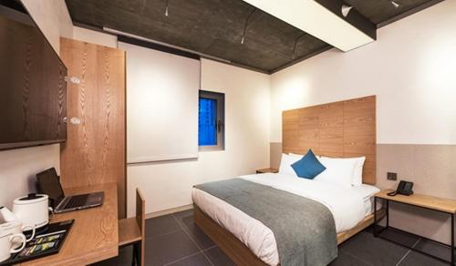 a bedroom with a bed and a desk with a laptop at Delight Hotel Jamsil in Seoul