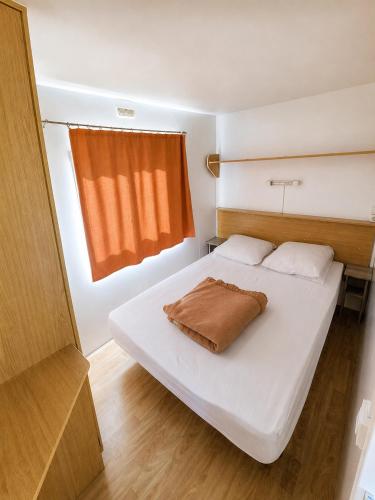 a bedroom with a white bed with a brown blanket on it at Camping Nysa Paziols in Paziols