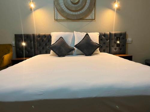 a large white bed with two pillows on it at Hôtel Le Castanea Entre Aurillac et Marcolès Auvergne in Roannes-Saint-Mary
