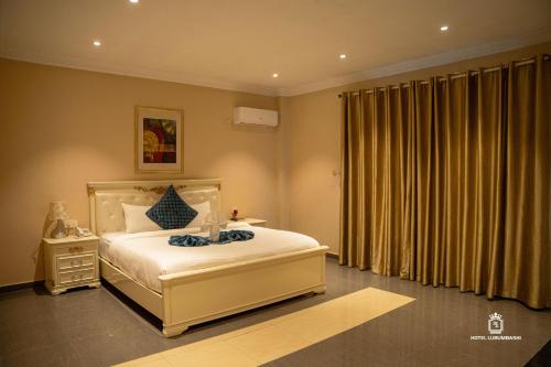 a bedroom with a large white bed and a window at Hotel Lubumbashi Golf in Lubumbashi