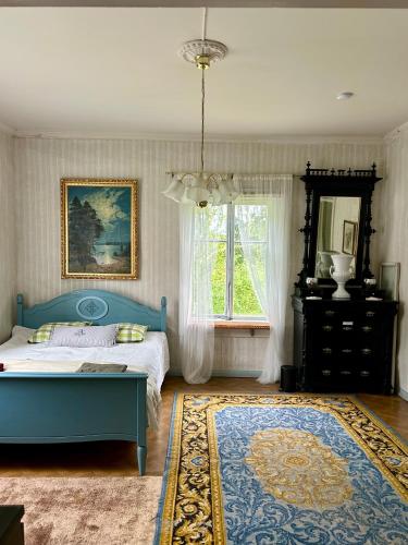 a bedroom with a blue bed and a window at Tunnelmallinen maalaistaloelämys in Vehmaa
