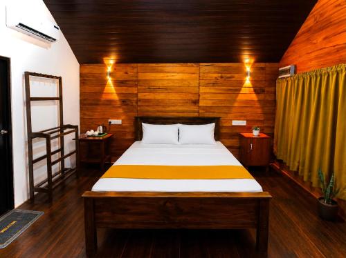 a bedroom with a bed with a wooden wall at Nethmini Leege Cottage in Kibissa