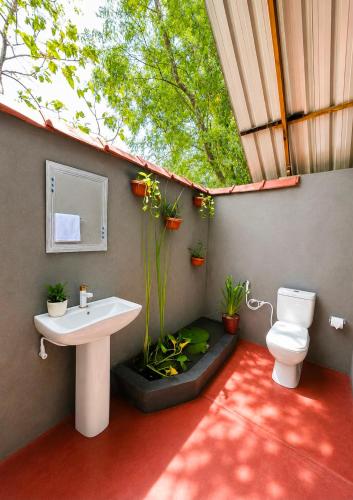 a bathroom with a sink and a toilet and a window at Nethmini Leege Cottage in Kibissa