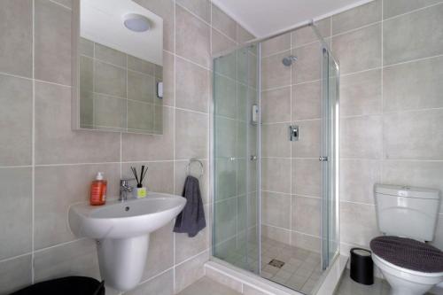 a bathroom with a shower and a sink and a toilet at #AlimamaSpaces Pano's Greenpark in Boksburg