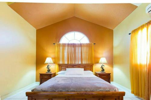 a bedroom with a large bed and a window at Caribbean Estate AJ in Portmore