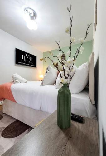 a green vase with flowers on a table next to a bed at Modern Large 5-Bed-2 Baths-Parking-Great for Groups-Contractors-Families-Royal Leamington Spa-Warwickshire-By The Home Makers Hub in Leamington Spa