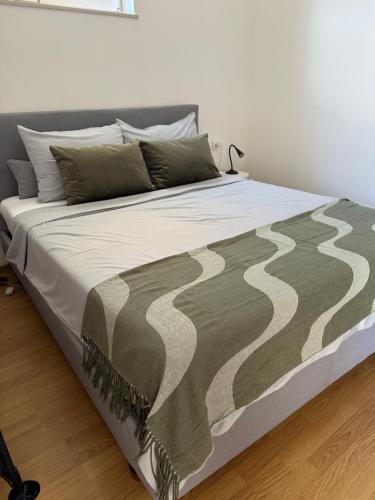 a bed with a green and white blanket on it at Apartman Zlata in Buzdohanj