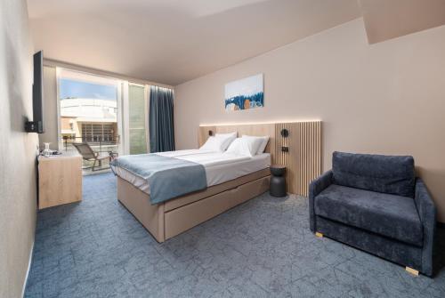 a bedroom with a bed and a chair at Family Hotel Adria - All inclusive in Biograd na Moru