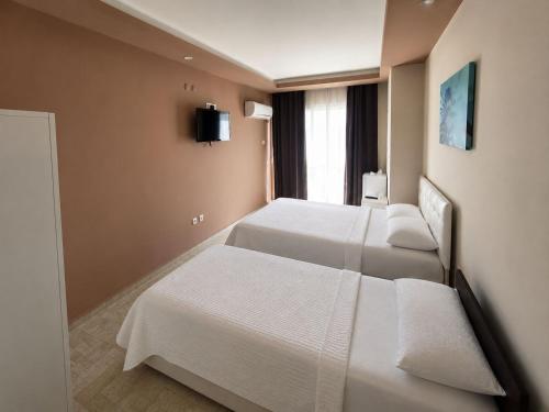 a hotel room with two beds and a television at Atlas Butik Otel in Kizkalesi
