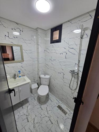 a white bathroom with a toilet and a sink at Appartement RDJ in Dar Hamida