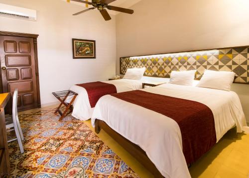 Habitación de hotel con 2 camas y ventilador de techo. en Hotel Caribe Merida Yucatan en Mérida